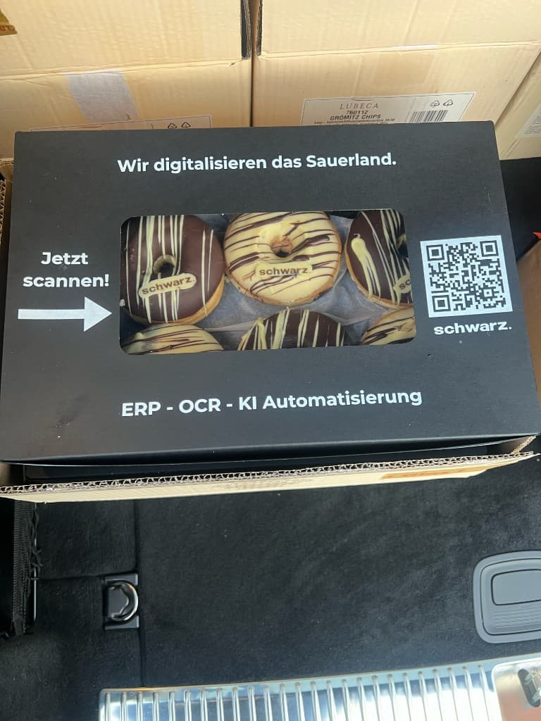 Nahaufnahme der schwarz. Donut-Box mit QR-Code und dem Slogan Wir digitalisieren das Sauerland